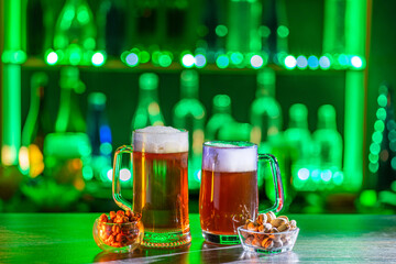Mugs of green beer, ale on the bar counter. Holiday of Ireland on St. Patrick's Day in irish pub,...
