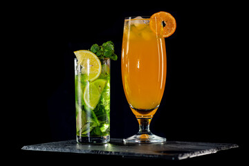 Cocktail mojito with ice on bar counter in a restaurant, pub. Orange drink, lime juice, mint. Fresh...