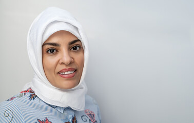 Portrait of middle-aged muslim woman wearing hijab head scarf over white background while looking...