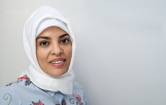 Portrait Of Middle-aged Muslim Woman Wearing Hijab Head Scarf Over White Background While Looking At Camera. Face Of Cheerful Woman Covered With Headscarf Smiling. Casual Islamic Girl. Copy Space