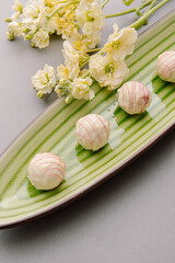 Tasty sweet truffles on green plate. Cheese truffles and flowers