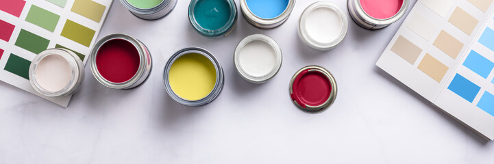 Tiny sample paint cans during house renovation, process of choosing paint for the walls, different colors, color charts on background, banner size