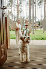 Vertical portrait of cute little dog walking into new home with family