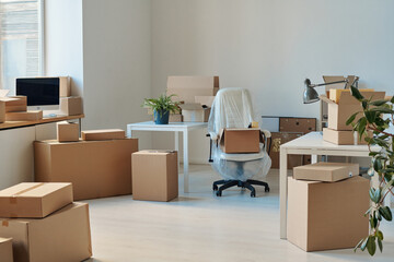 Horizontal image of big light office with furniture and packed cardboard boxes