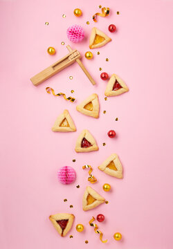 Hamantaschen Cookies, Red Carnival Mask, Noisemaker on Pink Background. Purim Celebration, Jewish Carnival Holiday Concept.