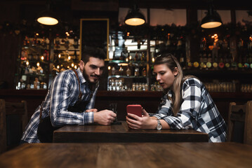 Millennial hipsters husband and wife owners of cafe bar restaurant sitting in the evening after closing talking checking profit, sales calculating order for the next day and resting after a busy day