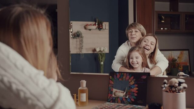 Three generations of women of a happy family. Grandmother, Young daughter and little granddaughter spend time hugging, smiling, laughing in front of the mirror. Mothers. Vivid emotions. 
