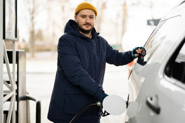 Man refueling his american SUV car at the gas station in cold weather.