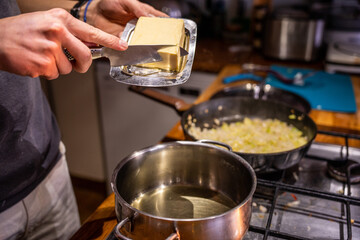 Obraz na płótnie Canvas A boy putting butter in a cooking pot.