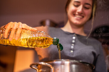 Girl cooking by putting oil in a pot.