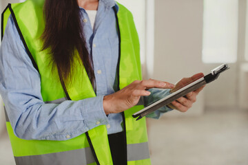 woman Industrial Engineer in High-Visibility Vest Working on Tablet Computer. Inspector or Safety Supervisor in construction site