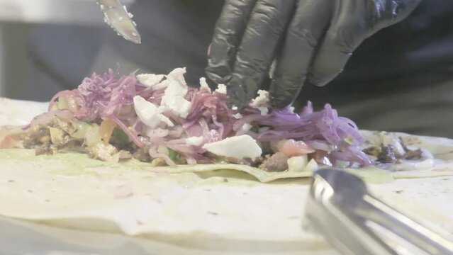 Cocinero preparando comida mediterranea, mexicana, oriental, con carne, pollo, cerdo envolviendo el pan &aacute;rabe grabado en camara lenta