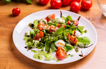 Plate of healthy classic close-up caprese salad with mozzarella cheese tomatoes and basil in kitchen - italian cuisine