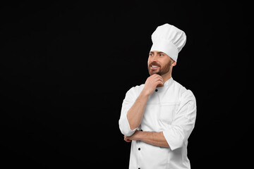 Naklejka premium Smiling mature chef on black background, space for text