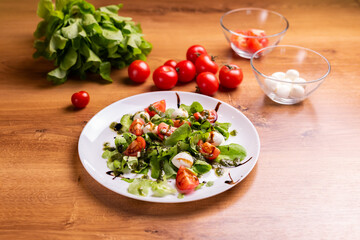 Plate of healthy classic close-up caprese salad with mozzarella cheese tomatoes and basil in kitchen - italian cuisine