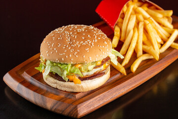 Delicious hamburger with two meats, cheddar cheese, fried egg, sauce and salad. Accompanied by french fries.