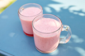 Two pink fruit and milkshakes in glass cups