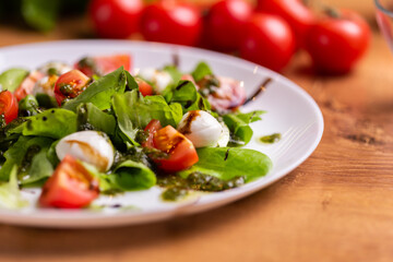 Plate of healthy classic close-up caprese salad with mozzarella cheese tomatoes and basil in kitchen - italian cuisine