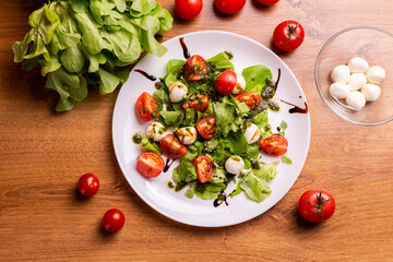 Plate of healthy classic top view caprese salad with mozzarella cheese tomatoes and basil in kitchen - italian cuisine