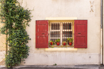 Red shutters on a barred window in the south of France.