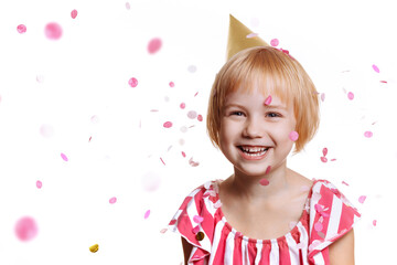 Portrait of a cute baby girl in a birthday dress. Cheerful child in a cap isolate on a white background with pink confetti flying around.