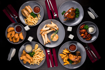 Combo snacks composition with chicken wings, lamb ribs, sausages, fried shrimp, onion rings, nuggets fish and french fries