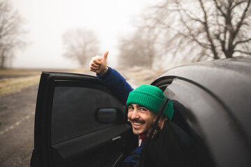 The car driver looks at the camera. Smiling taxi driver. Driver A friendly and friendly man offers...