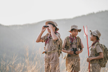 A boy in a hat holding a binocular Boy scouts working on mountains nature adventures and travel - obrazy, fototapety, plakaty