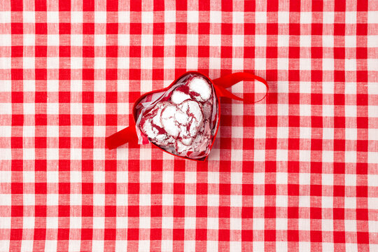 red box in the shape of a heart with cookies for valentine's day on a red checkerd tablecloth