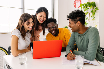 Group of cheerful millennial people study together at home. Multiracial college students learning with laptop preparing for university exam.