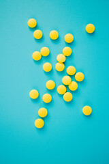 Chaotically arranged yellow pills on a blue background, healthy and medicine concept