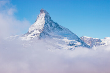 Mount matterhorn peaks out of clouds on a suny day with blue sky