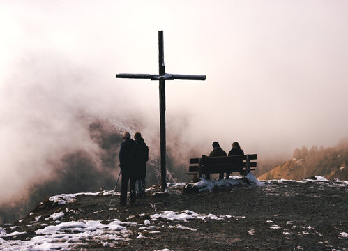 people sitting and standing near a cross