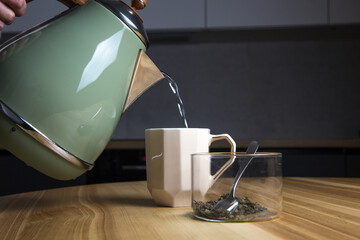 pouring hot water from an electric kettle into a tea cup