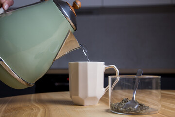 pouring hot water from an electric kettle into a tea cup