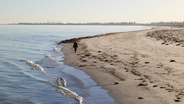 Man Walks Alone on Beach in Semaphore During a Winter Morning