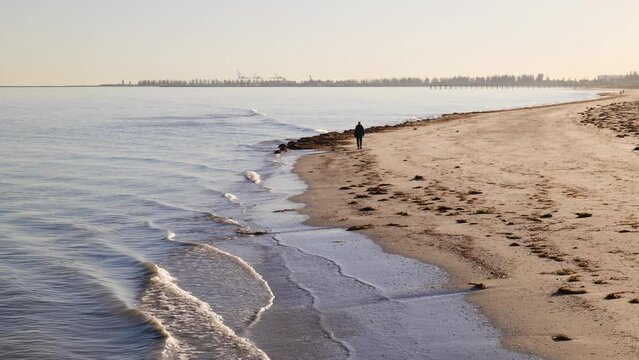 Man Walks Alone on Beach in Semaphore During a Winter Morning