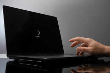 An impatient man tapping his fingers waiting for a loading screen on a laptop.