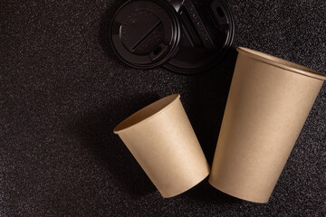 two paper opened coffee cup on a black speckled background top view