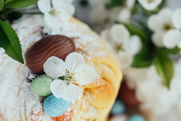 Obraz na płótnie Canvas Traditional cupcake Easter cake kraffin with raisins on blue background. Cherry blossom, choco eggs. Close up of homemade cake. Cruffin with candied fruits. Food. Copy space.