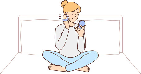 Woman sitting on bed doing makeup