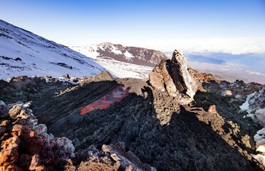Etna in inverno con neve e cielo blu durante l' eruzione con colata di lava incandescente che scorre