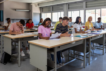 Young group of high school students studying in classroom