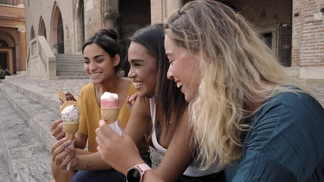 Three young woman eating ice cream cones at the touristic European Roman city on a hot summer day during their vacation. High quality photo