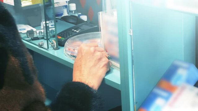 Senior woman buys medicines in a pharmacy while standing at the checkout. Closeup