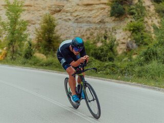 Obraz premium Full length portrait of an active triathlete in sportswear and with a protective helmet riding a bicycle. Selective focus 