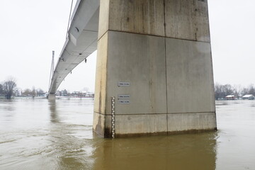 Sremska Mitrovica, Serbia, 01.27.2023 Bridge over the river Sava. Flooding after heavy rains and melting snow. A swift flow of muddy water. Hydrological scale for measuring the level of water.