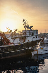 Beautiful evening cinematic photo, visible mountains, sunset, clouds and yellow sky, sea, boats in shadow, harbor, many boats at the pier, sun glare and water reflecting ships