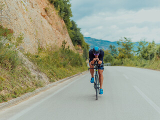 Full length portrait of an active triathlete in sportswear and with a protective helmet riding a bicycle. Selective focus 