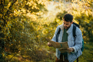 Shot of a young hiker holding a map while taking in the view from the hill.